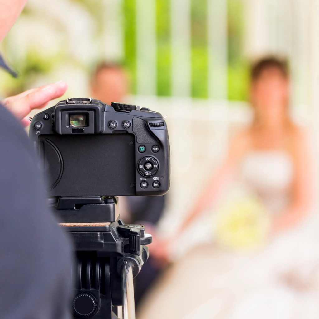 Titelbild des Lexikoneintrages: Hochzeitsfotograf. Zu sehen ist ein Fotograf, der ein Hochzeitspaar ablichtet.