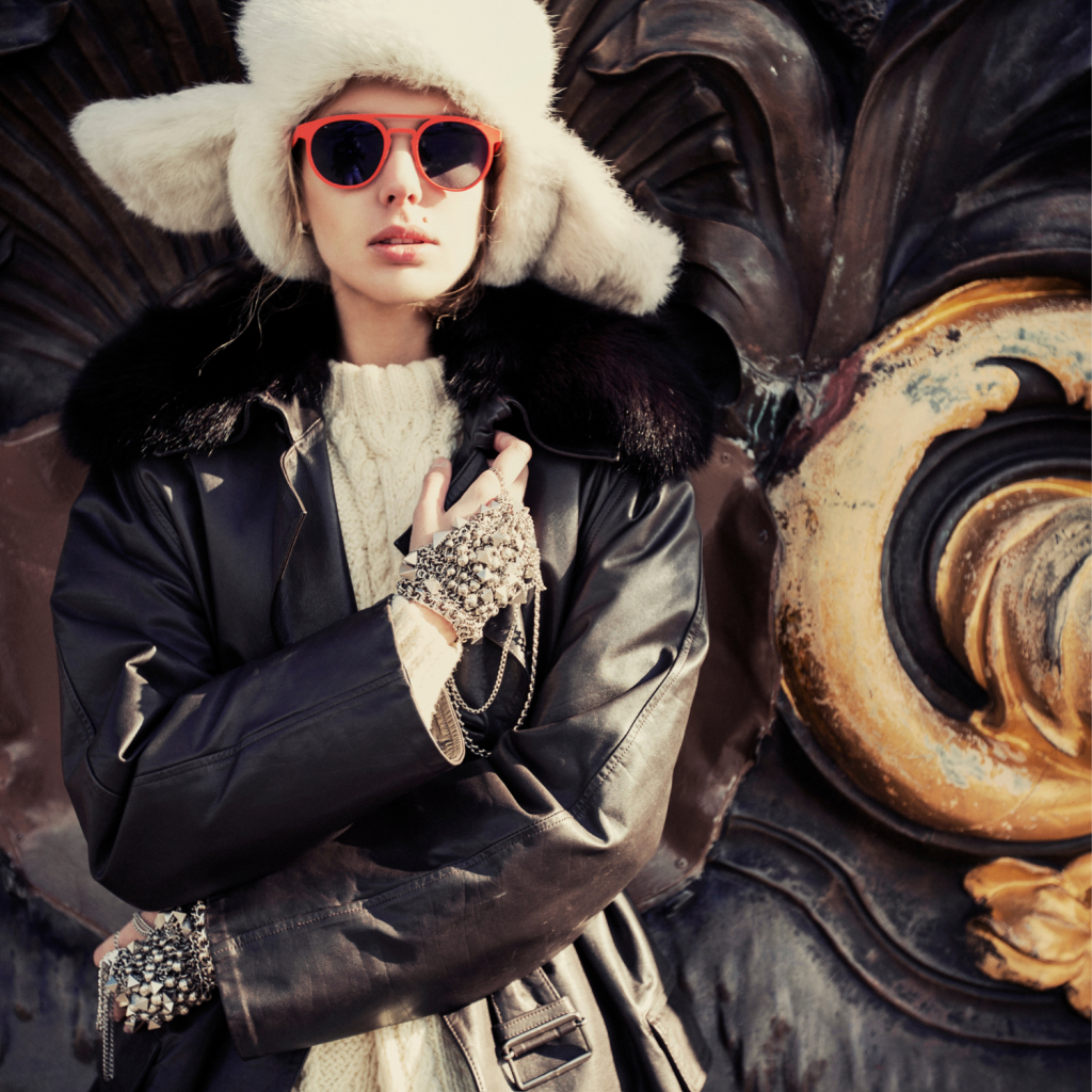 Tietelbild der Modefotografie. Zu sehen ist ein Model mit roter Sonnenbrille und Winterkleidung. Auf dem Kopf trägt sie eine weiße Wintermütze